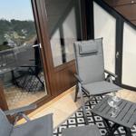 Terrasse mit Sitzgelegenheit und Tisch. Blick auf grüne Landschaft.