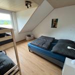 Schlafzimmer mit Doppelbett, Etagenbett und Fenster mit Blick auf Landschaft.