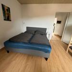 Schlafzimmer mit Doppelbett und Kletterbett. Holzboden und Wandbild.