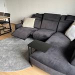 Ein großes graues Sofa mit Kissen und einem runden Teppich im Wohnzimmer.