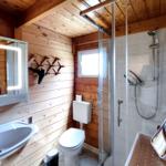 Modernes Badezimmer mit Glasedelstahl-Dusche und beleuchtetem Spiegel