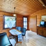 Wohnzimmer mit Holzwand, Sofa, Tisch, Stühle und Fernseher.