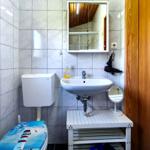 Badezimmer mit Waschbecken, Spiegel, Toilette und Fenster.