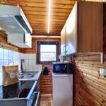 Küche mit Holzwand, Spüle, Herd, Kühlschrank und Mikrowelle.