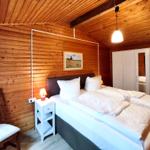 Schlafzimmer mit Holzwand, Bett, Nachttisch und Kleiderschrank.