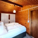 Schlafzimmer mit Holzwand, Bett, Kleiderschrank und Tür