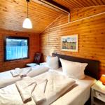 Schlafzimmer mit Holzwand, Bett, Nachttisch und Fenster.