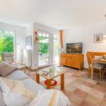 Wohn- und Essbereich mit Sofa, TV und Terrassentür.
