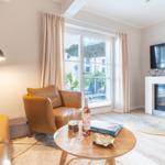 Wohnzimmer mit Ledersofa, TV und Kamin. Durchgangsfenster mit Blick auf Balkon.