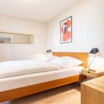 Schlafzimmer mit Holzbett, Nachttisch und Wandbild.