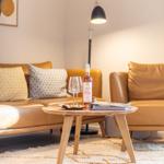 Ein Wohnzimmer mit braunem Sofa, Tisch und Weinflasche.