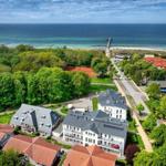 Aerial view of coastal village with houses, trees, and ocean in background.