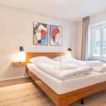 Schlafzimmer mit Doppelbett, Holzfußboden und Fenster mit Vorhängen.