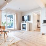 Wohnzimmer mit Sofa, Fernseher und Kamin. Durchgang zur Schlafzimmer. Küche mit Mikrowelle.