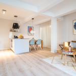 Wohn- und Essbereich mit Küche, Sofa und Tisch. Holzboden und moderne Einrichtung.