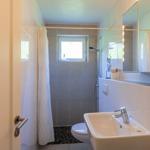Badezimmer mit Dusche, Toilette und Waschbecken. Fenster sorgt für Tageslicht.