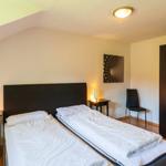 Zimmer mit zwei Betten, Schrank und Nachttisch mit Lampe.