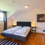 Zimmer mit Doppelbett, zwei Nachttischen, Schrank und Fenster mit Blick.