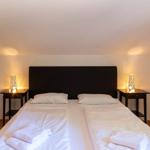 Schlafzimmer mit Doppelbett, zwei Nachttischen und Beleuchtung.