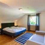 Schlafzimmer mit Doppelbett, Sofa und Fenster mit Blick nach draußen.