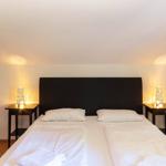 Schlafzimmer mit Doppelbett, zwei Nachttischen und Lampen an den Wänden.