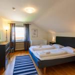 Schlafzimmer mit Doppelbett, Kleiderschrank und Fenster mit Vorhängen.