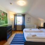 Schlafzimmer mit Doppelbett, Babybett, Schrank und Fenster mit Vorhängen.