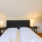 Schlafzimmer mit Doppelbett, zwei Nachttischen und einem Kinderbett.