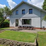 Haus mit Terrasse, Garten und Sitzgelegenheiten. Modernes Design mit Holz- und Putzfassade.