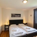 Schlafzimmer mit Doppelbett, zwei Nachttischen und Fenster mit Vorhängen.