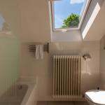 Badezimmer mit Dachfenster, Badewanne, Toilette und Heizkörper.