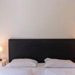 Schlafzimmer mit Bett, zwei Nachttischen und Lampen an den Seiten.