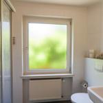 Badezimmer mit Dusche, Fenster und Waschbecken