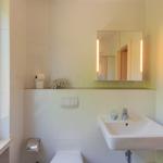 Badezimmer mit Waschbecken, Spiegel und Fenster. Toilettenpapier und Seife sind vorhanden.