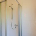 Dusche mit Glaswand und Handbrause an der Wand