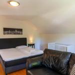 Schlafzimmer mit Doppelbett, Sofa und Wiege. Holzboden und schlichte Einrichtung.