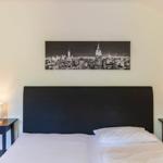 Schlafzimmer mit Bett, Nachttischen und Wandbild von New York
