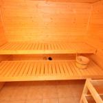 Sauna mit Holzbanken und Eimer. Bodenfliesen und Holzwände.