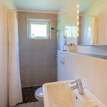 Badezimmer mit Dusche, Waschbecken und Toilette. Fenster sorgt für Tageslicht.