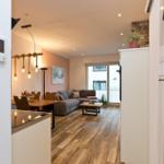 Wohnbereich mit Sofa, Tisch und Holzboden. Küche mit Thermostat und Lichtschalter.