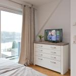 Schlafzimmer mit TV, Balkon und Blick auf den See.