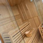 Sauna mit Holzbank, Holzschale und Glaswand.