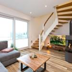 Wohnzimmer mit Sofa, Kamin, Fernseher und Holztreppe.