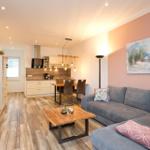 Wohnzimmer mit Sofa, Kamin und offener Küche im Hintergrund.