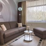 Wohnzimmer mit Sofa, Sitzbank und Tisch vor großem Fenster.