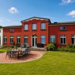 Rotes Haus mit Garten und Terrasse mit Tisch und Stühlen.