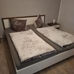 Schlafzimmer mit Doppelbett, Bettwäsche mit Blumenmuster und Nachttisch.