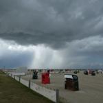 Strand mit bunten Strandkörben unter dunklem Himmel.