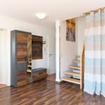Eingangsbereich mit Kleiderschrank, Treppe und Bad. Holzfußboden und Gardine.