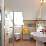 Badezimmer mit Dusche, Toilette und Waschbecken unter Dachschrägen.